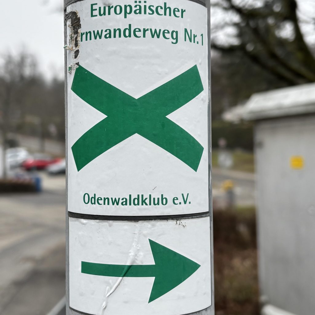 Ein Wegweiser des E1 mit Andreaskreuz und Richtungspfeil